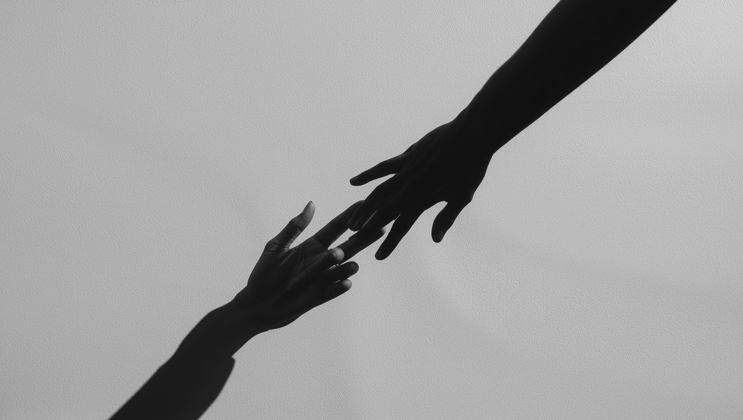 Two silhouetted hands reaching toward each other, fingertips nearly touching