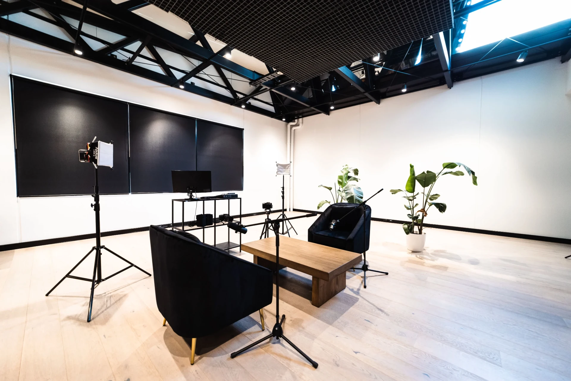 A recording studio set with two armchairs, a table and filming equipment